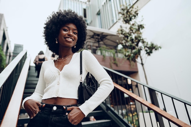 Jeune femme africaine souriante pose près des escaliers de la ville