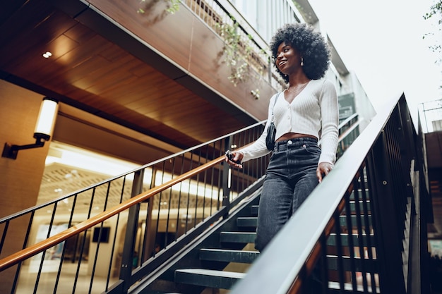 Jeune femme africaine souriante pose près des escaliers de la ville