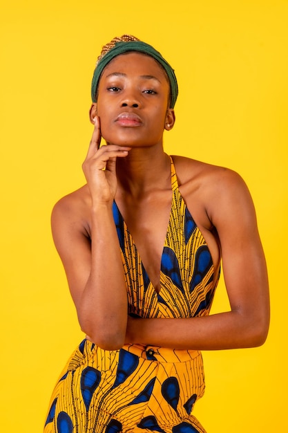 Jeune femme africaine en studio sur fond jaune portrait en costume traditionnel regardant la caméra