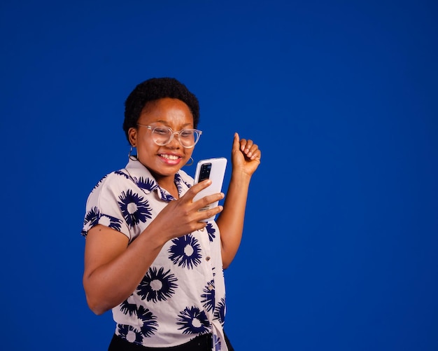 Jeune femme africaine surprise utilisant un téléphone portable avec une expression positive