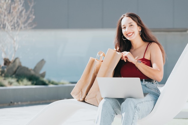 Jeune femme africaine utilisant un ordinateur portable pour faire du shopping à l'extérieur avec espace de copie. Fille hipster heureuse et branchée commandant de la nourriture en ligne, réservant des billets pendant une journée ensoleillée. Jeunes branchés