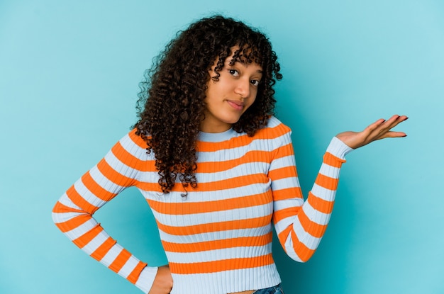 Jeune femme afro-américaine afro-américaine doutant et haussant les épaules dans un geste de questionnement.