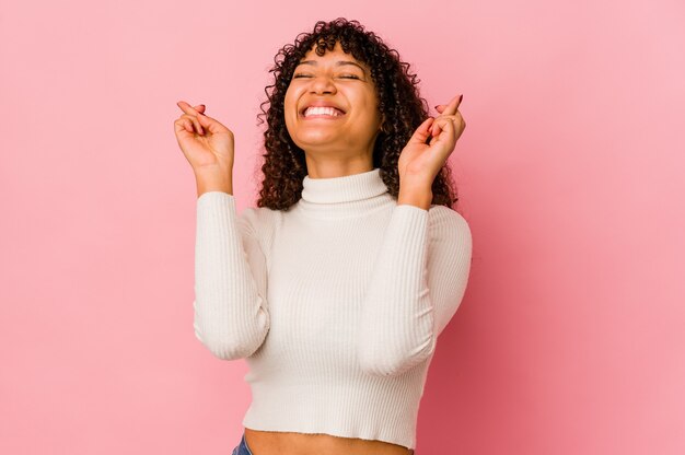 Jeune femme afro-américaine afro-américaine isolée des doigts croisés pour avoir de la chance