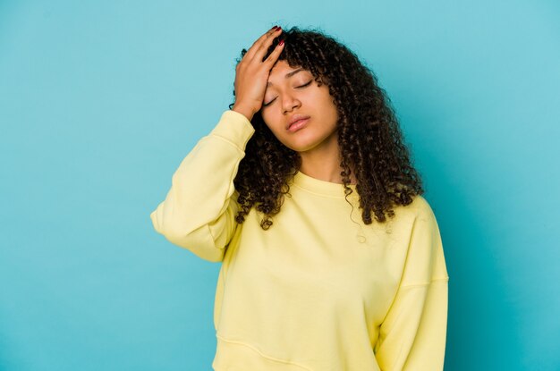 Jeune femme afro-américaine afro-américaine isolée fatiguée et très endormie en gardant la main sur la tête.