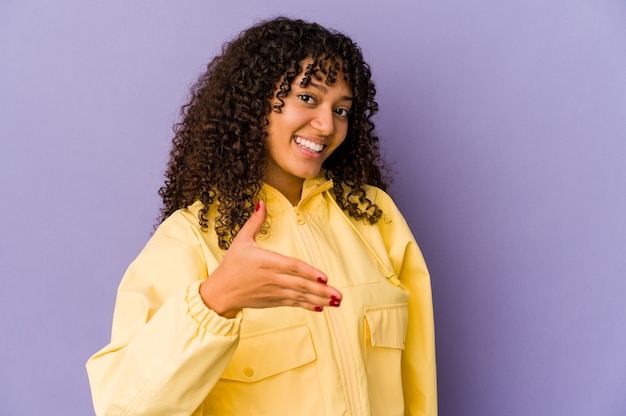 Jeune femme afro-américaine afro-américaine isolée main étirement à la caméra en geste de salutation.