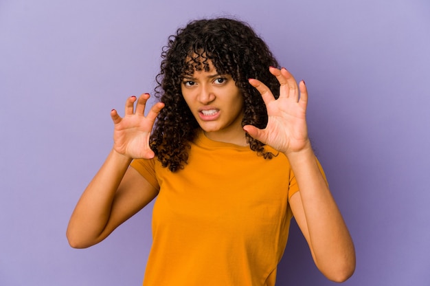 Jeune femme afro-américaine afro-américaine isolée montrant des griffes imitant un chat, geste agressif.