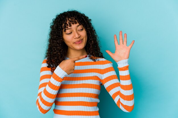 Jeune femme afro-américaine afro-américaine isolée souriant joyeux montrant le numéro cinq avec les doigts.