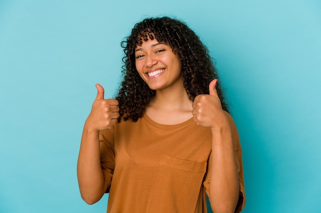 Jeune femme afro-américaine afro-américaine isolée souriant et levant le pouce vers le haut