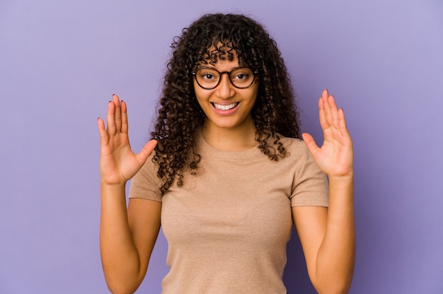 Jeune femme afro-américaine afro-américaine isolée tenant quelque chose de peu avec les index, souriant et confiant.