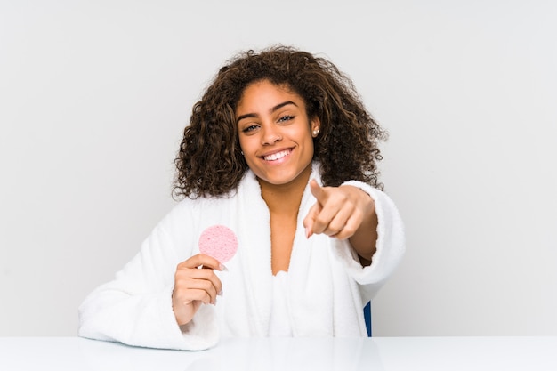 Jeune femme afro-américaine à l'aide d'un disque facial sourires joyeux pointant vers l'avant.