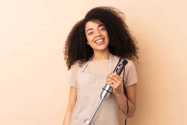 Jeune femme afro-américaine à l'aide d'un mélangeur à main isolé