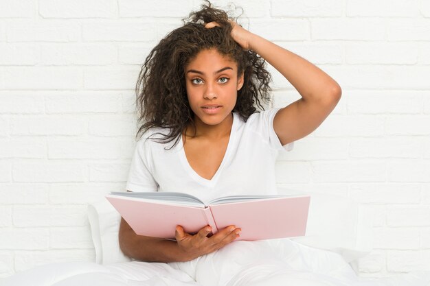 Jeune femme afro-américaine assise sur le lit étudiant en état de choc, elle s'est souvenue d'une réunion importante.