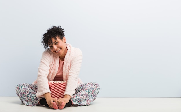 Jeune femme afro-américaine assise tenant une boîte de pop-corn