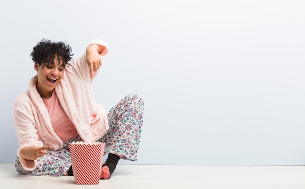 Jeune femme afro-américaine assise tenant une boîte de pop-corn