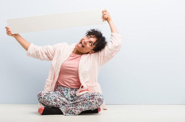 Jeune femme afro-américaine assise tenant une pancarte