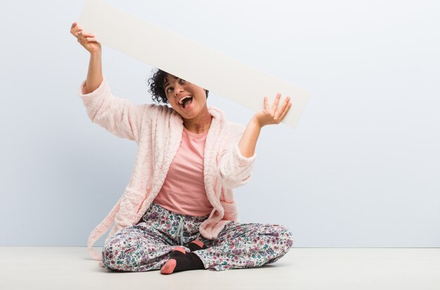 Jeune femme afro-américaine assise tenant une pancarte