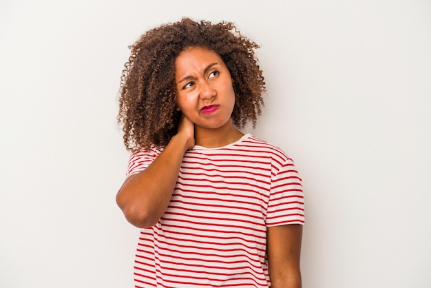 Photo jeune femme afro-américaine aux cheveux bouclés isolé sur fond blanc ayant une douleur au cou due au stress massant et le touchant avec la main