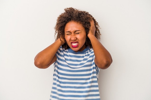 Jeune femme afro-américaine aux cheveux bouclés isolé sur fond blanc couvrant les oreilles avec les mains.