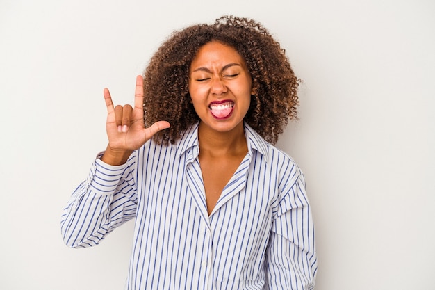 Jeune femme afro-américaine aux cheveux bouclés isolé sur fond blanc montrant un geste rock avec les doigts