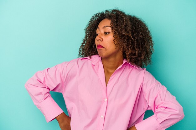 Jeune Femme Afro-américaine Aux Cheveux Bouclés Isolée Sur Fond Bleu Rêvant D'atteindre Ses Objectifs