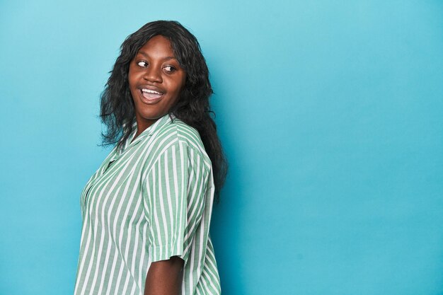 Une jeune femme afro-américaine bien roulée regarde de côté souriante joyeuse et agréable