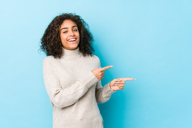 Jeune femme afro-américaine cheveux bouclés excité pointant avec les index loin.