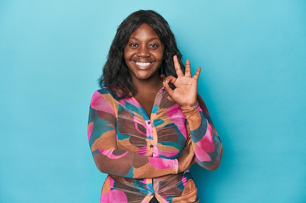 Une jeune femme afro-américaine courbée fait un clin d'œil et tient un geste correct avec la main