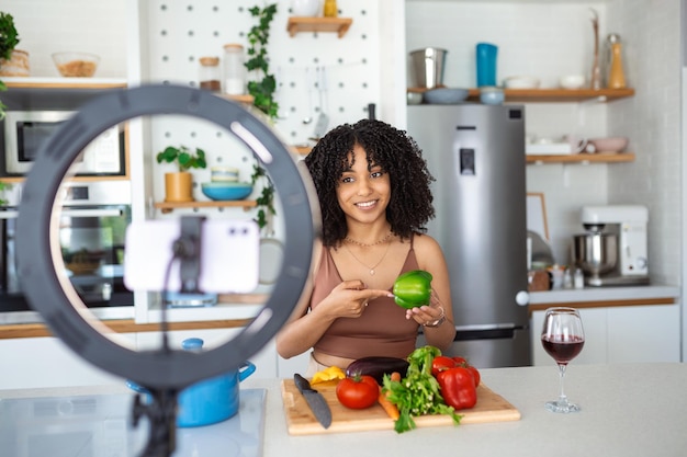 Jeune femme afro-américaine cuisine conférencier parlant sur un appareil photo numérique enregistrant vlog Femme africaine vlogger ou tournage blog filmant reportage publicité coaching vidéo