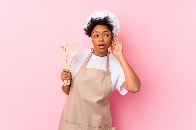 Jeune femme afro-américaine de cuisinier essayant d'écouter un commérage.