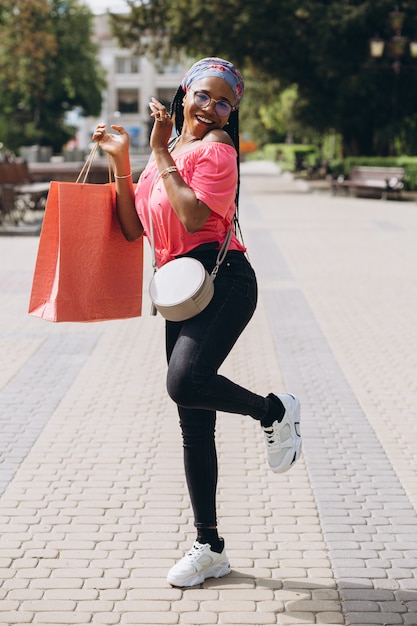 Jeune femme afro-américaine dans la rue avec des sacs à provisions
