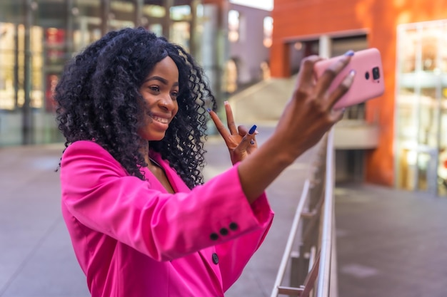 Jeune femme afro-américaine dans la ville portrait d'une jeune femme en veste rose prenant un selfie