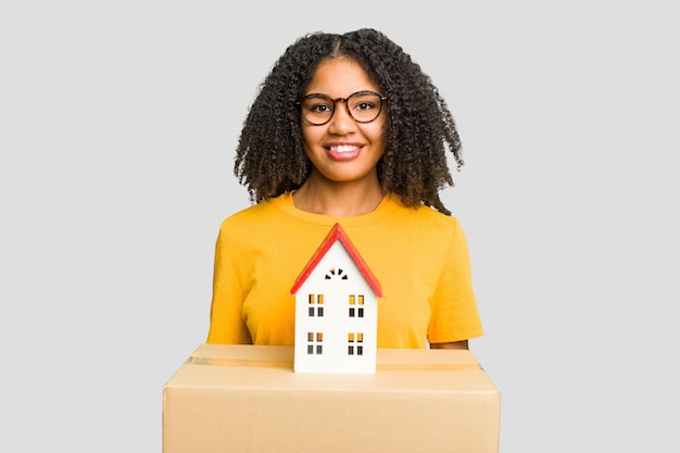 Jeune femme afro-américaine déménageant dans une nouvelle maison tout en ramassant une boîte pleine de choses isolées