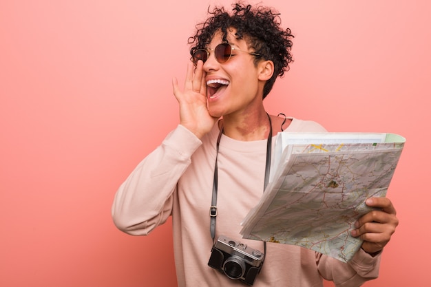 Jeune femme afro-américaine détenant une carte en criant excité à l'avant.