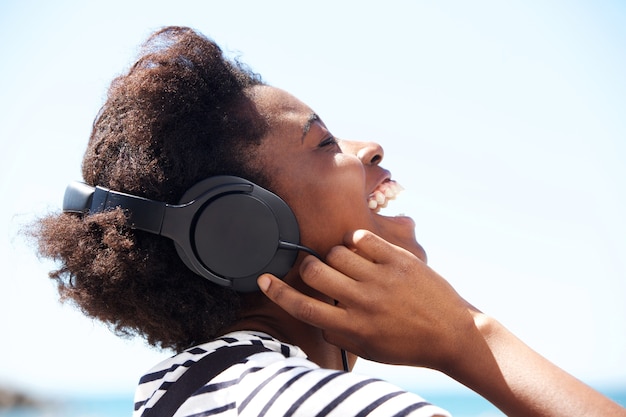 Jeune femme afro-américaine écoutant de la musique sur le casque et en riant