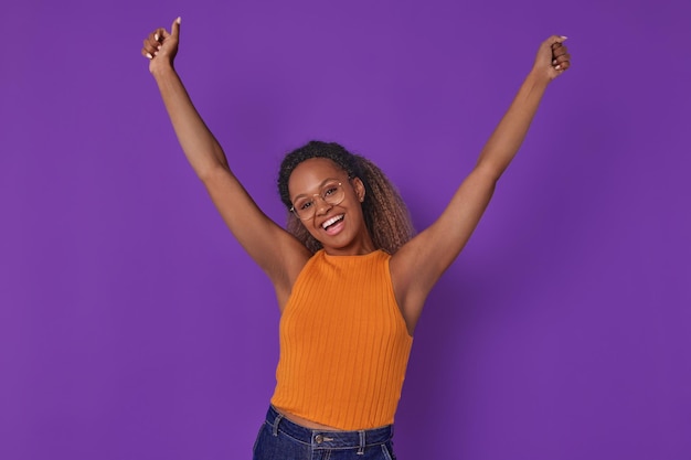 Photo une jeune femme afro-américaine enjouée lève les mains et se tient dans le studio.