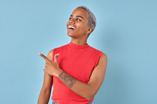 Photo une jeune femme afro-américaine enthousiaste pointe le doigt d'un côté et rit.