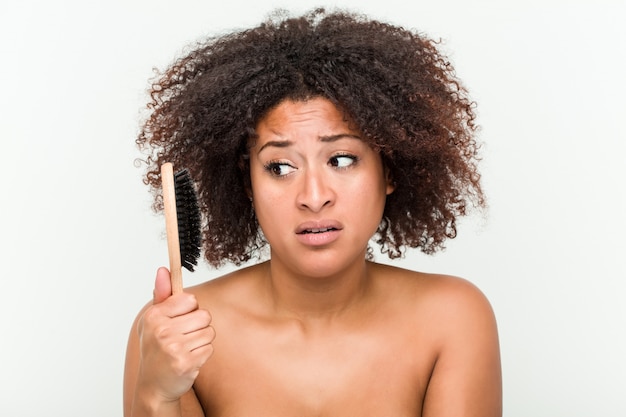 Photo jeune femme afro-américaine essayant de se brosser ses cheveux bouclés