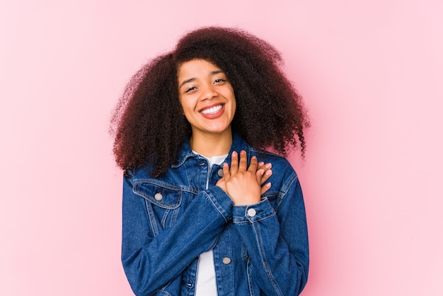 Jeune femme afro-américaine a une expression amicale, en appuyant la paume contre la poitrine. Concept d'amour.