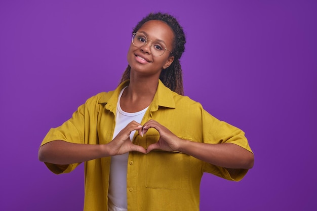 Jeune femme afro-américaine en forme de coeur avec les doigts et la tête inclinable