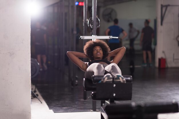 Jeune femme afro-américaine en forme faisant des redressements assis dans un studio de remise en forme à la salle de sport.Exercices abdominaux