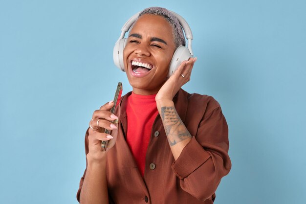 Une jeune femme afro-américaine heureuse chante en tenant un téléphone au lieu d'un micro.