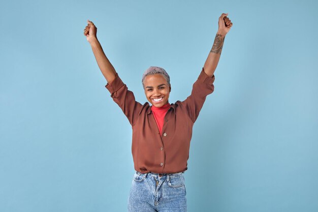 Photo une jeune femme afro-américaine heureuse lève victorieusement les mains dans le studio.