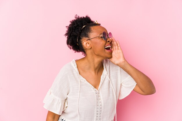 Jeune femme afro-américaine hipster isolée criant et tenant la paume près de la bouche ouverte.