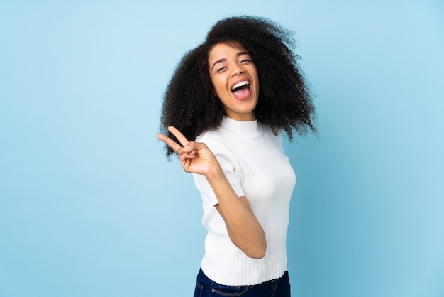 Jeune femme afro-américaine sur isolé souriant et montrant le signe de la victoire