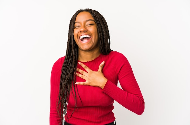 Jeune femme afro-américaine isolée éclate de rire en gardant la main sur la poitrine.