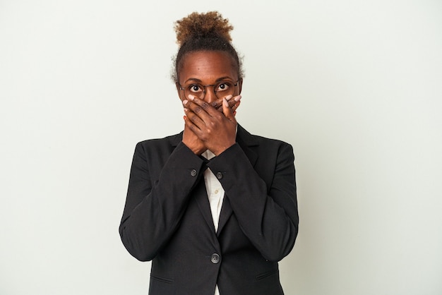 Jeune femme afro-américaine isolée sur fond blanc choqué couvrant la bouche avec les mains.