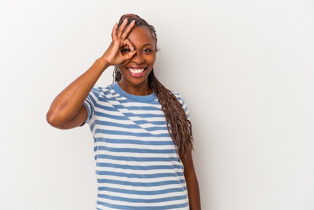 Jeune femme afro-américaine isolée sur fond blanc excitée en gardant un geste ok sur les yeux.