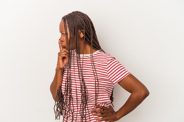 Jeune femme afro-américaine isolée sur fond blanc gardant un secret ou demandant le silence.