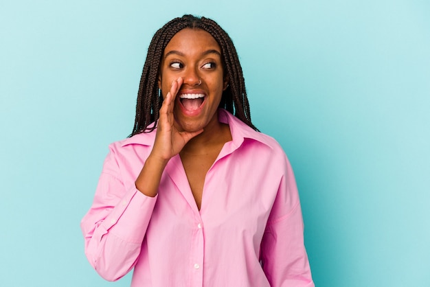 Jeune femme afro-américaine isolée sur fond bleu criant excitée à l'avant.