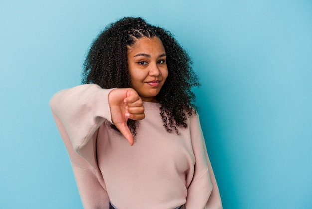 Jeune femme afro-américaine isolée sur fond bleu montrant le pouce vers le bas, concept de déception.